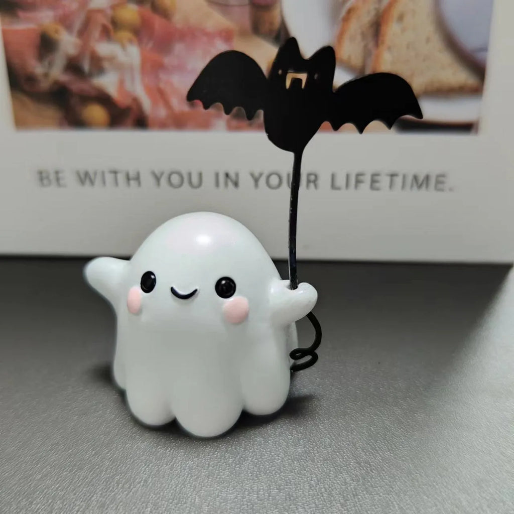 Miniature resin statue of a ghost holding a bat next to a walking dog, a Halloween decoration.
