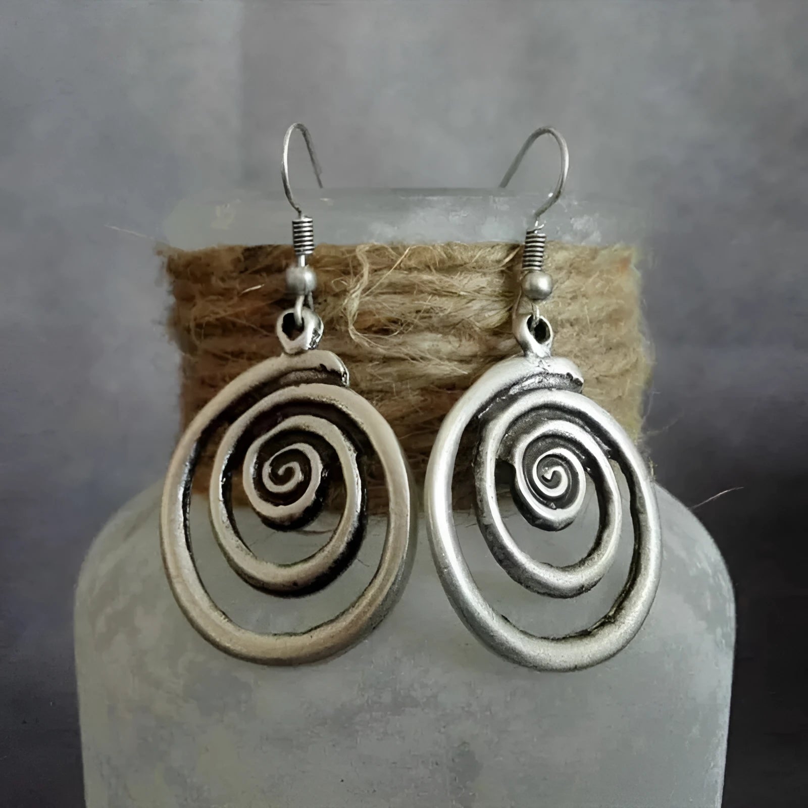 Geometric spiral alloy earrings with distressed silver finish and folk art style.
