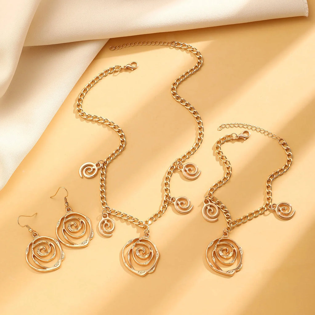 Gold tone spiral donut design necklace, bracelet, and earrings set on a white background.