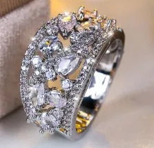 Women's hollow round fashion ring in gold tone with blue stones, showing openwork design.