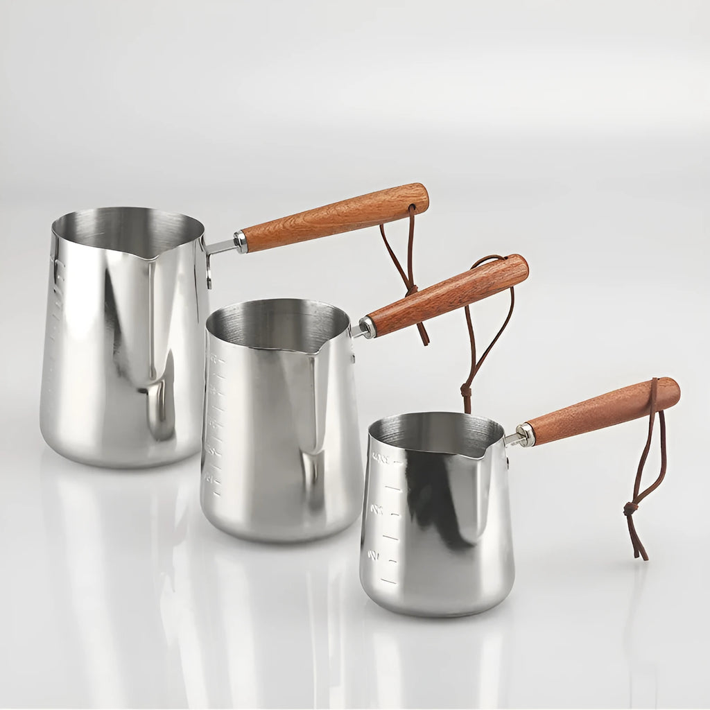 Stainless steel coffee cup with wooden handle showing interior measurement scale for latte art