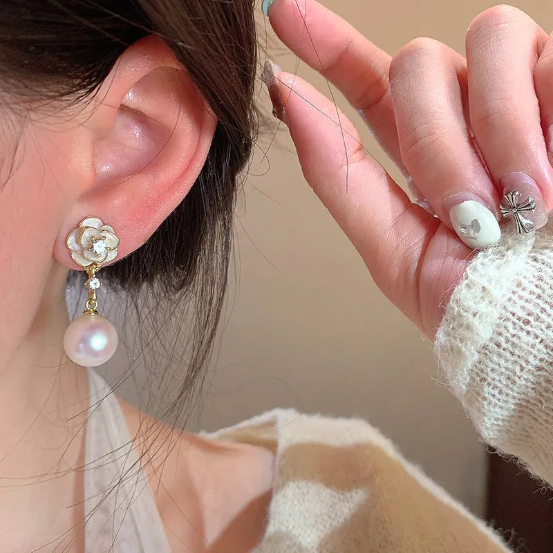 A pair of camellia flower stud earrings for women with a pearl centre, made from alloy.