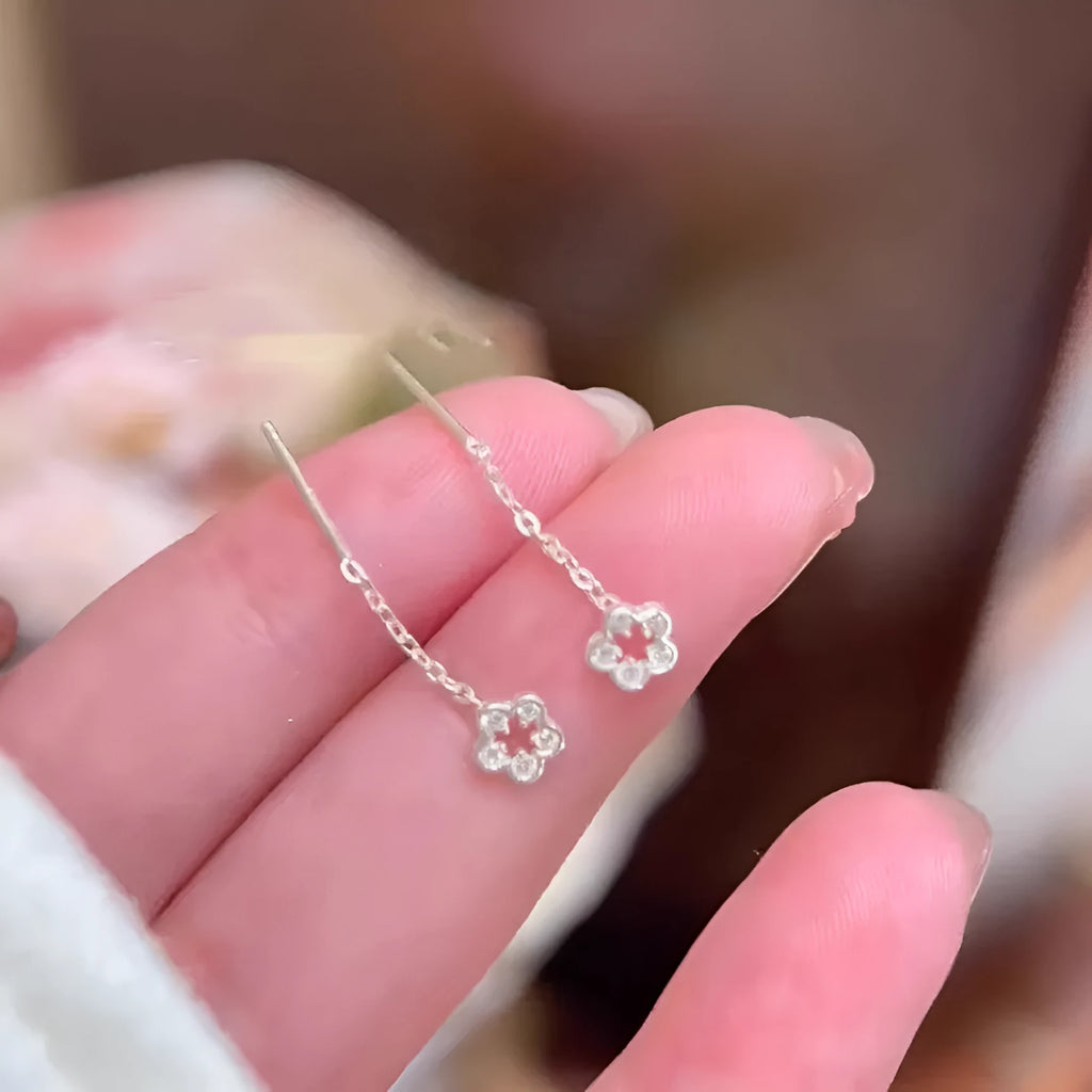 Silver hollow flower drop earrings with detailed petal design on hook closure