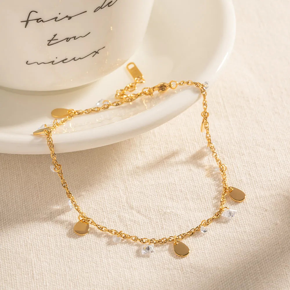 Stainless steel women's anklet with a water drop tassel charm and geometric details.