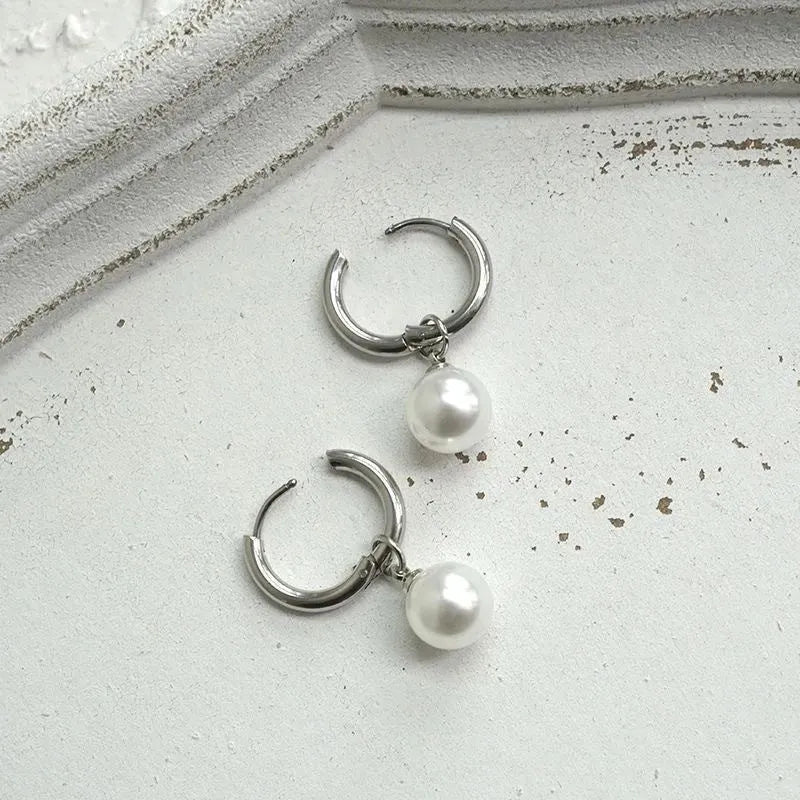 A pair of geometric pearl-coloured alloy earrings with titanium steel posts on a white background.