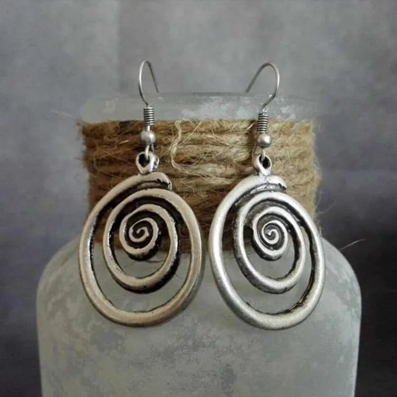 Geometric spiral alloy earrings with distressed silver finish and folk art style.