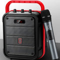 Portable black Bluetooth speaker with a wireless microphone, remote control, and carry strap.