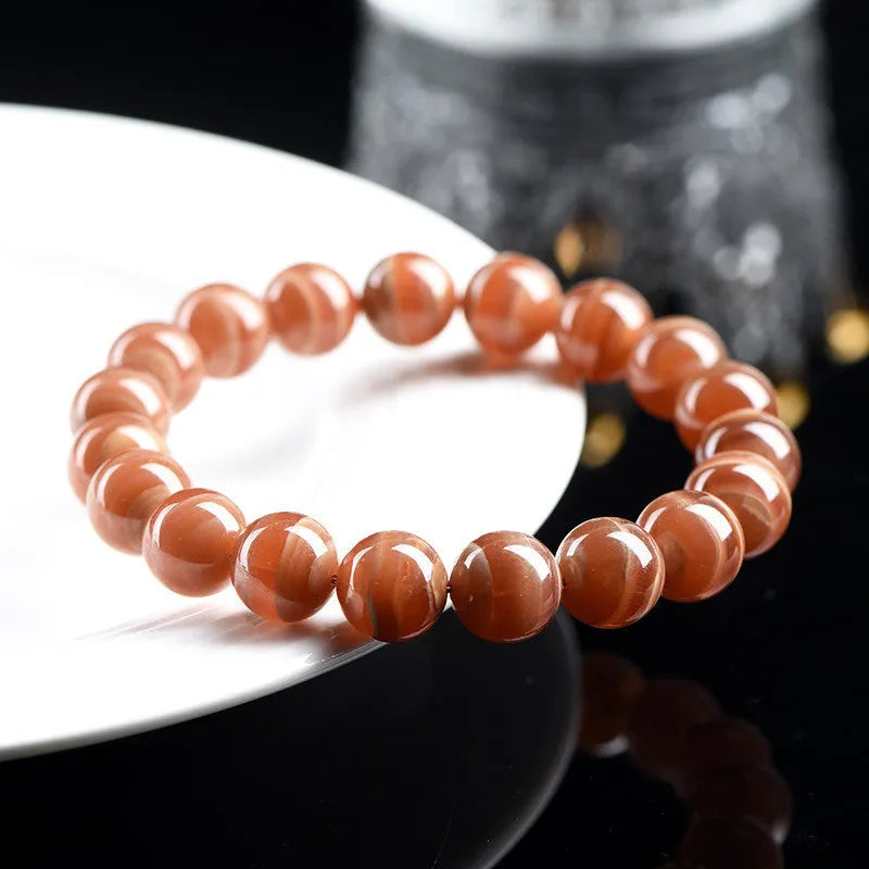 Natural old mine rhodochrosite round bead bracelet with Ruyi symbol on a wrist.