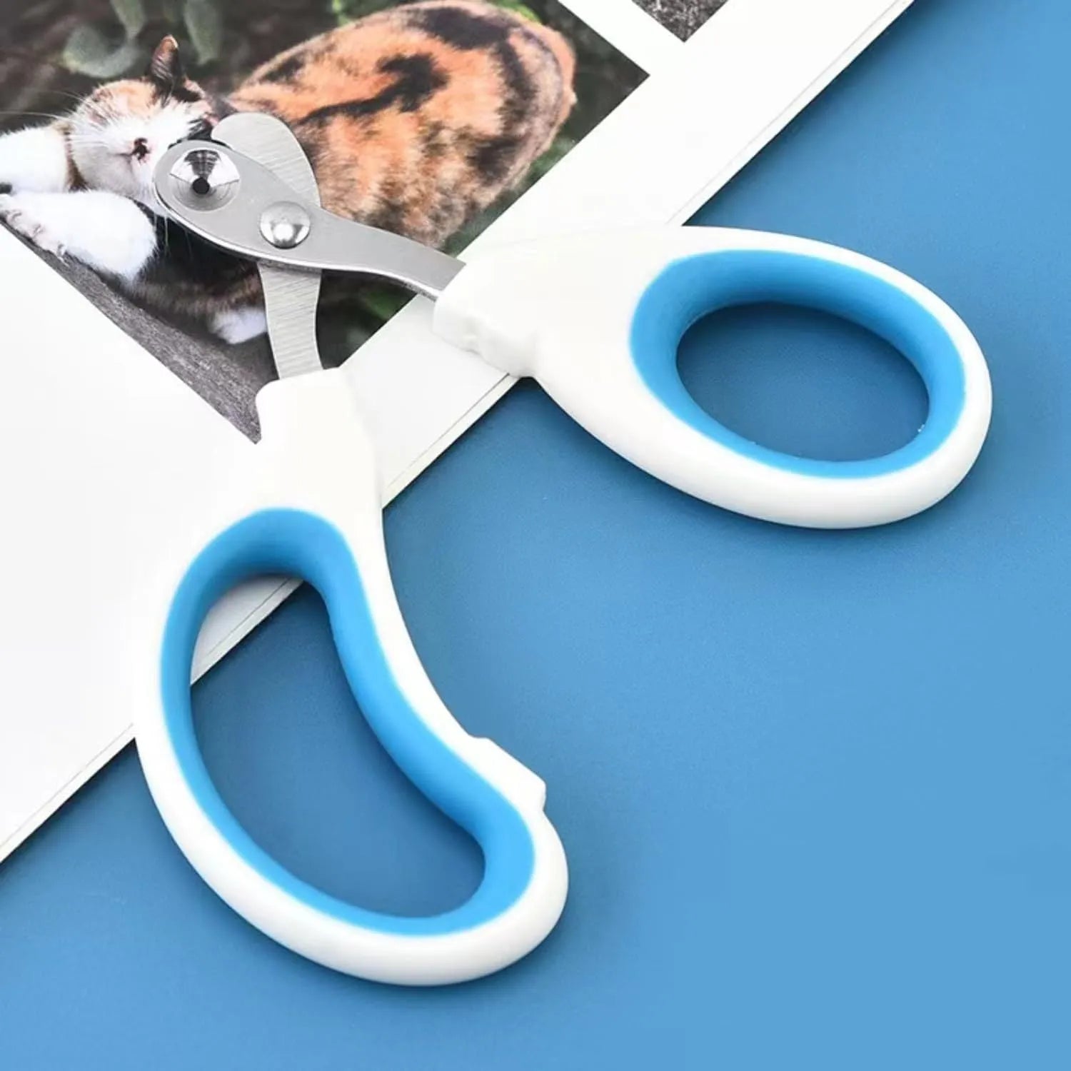 Blue cat nail clippers with a circular guide hole and non-slip grip handle on a white surface.