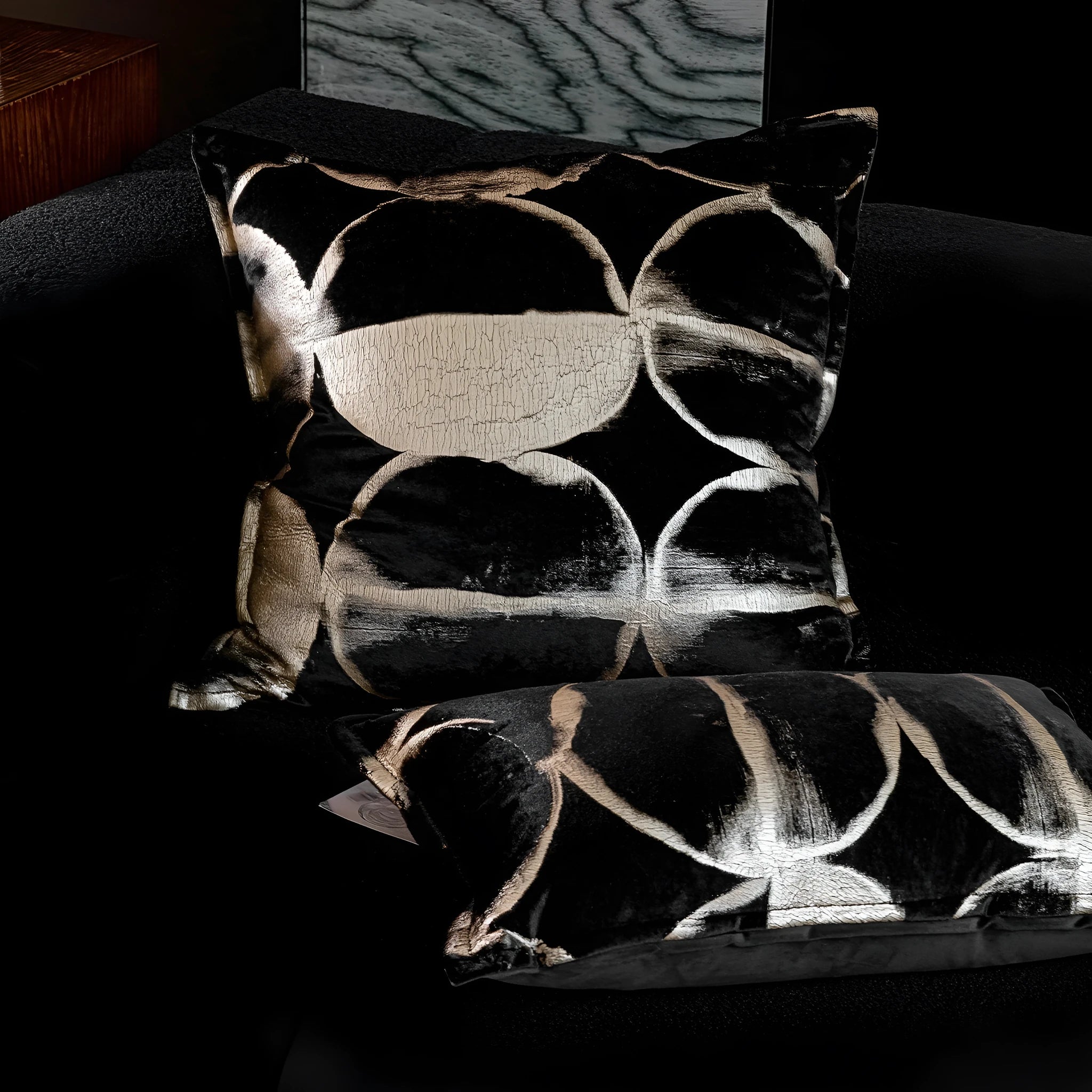 Abstract pattern black and gold decorative cushion pillow with removable cover on a grey sofa.