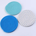 Set of three round grey cotton cord coasters on a wooden table