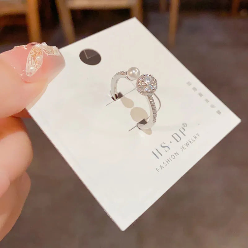 Open-end pearl ring with round zircon stones in gold plating on geometric copper base