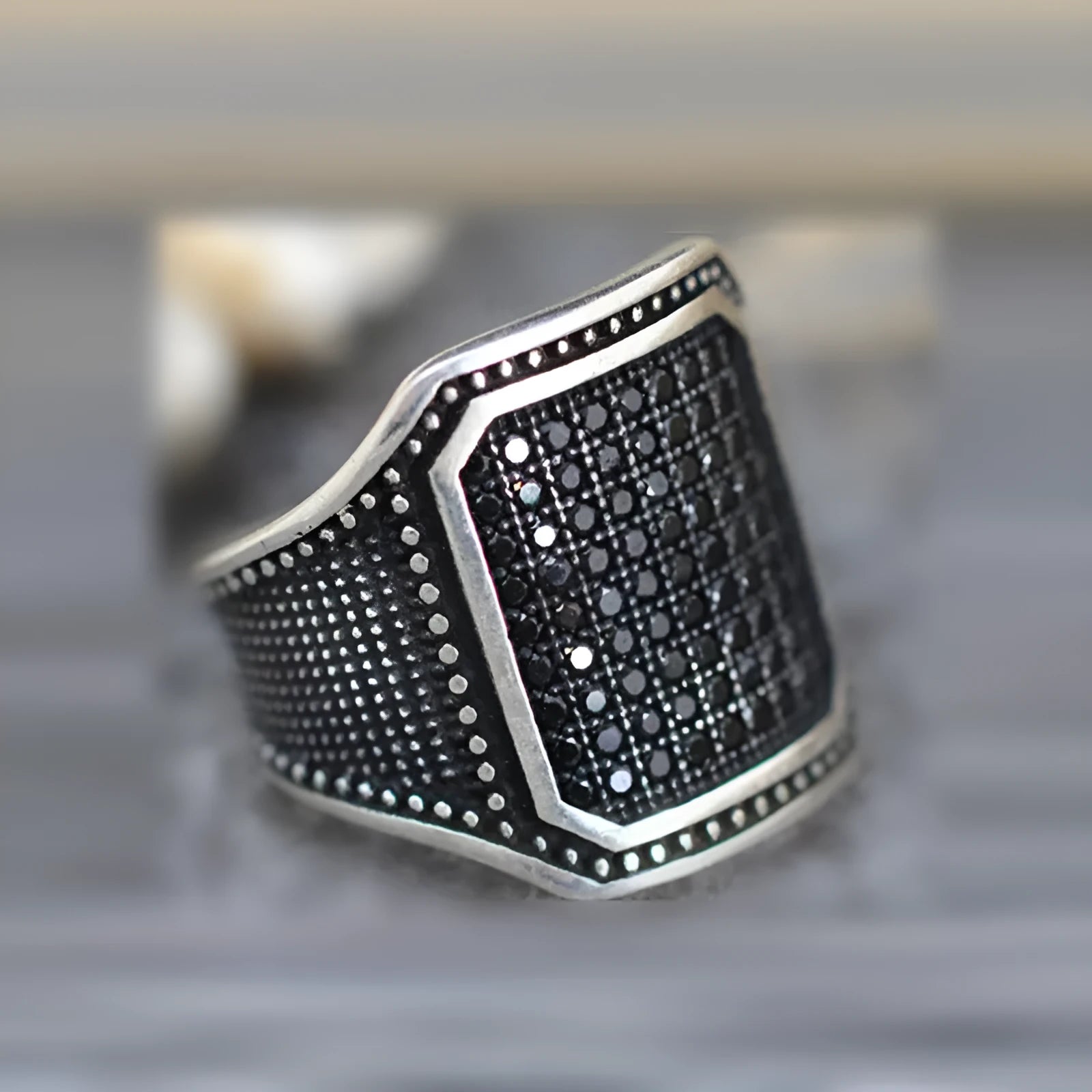 Black alloy ring with copper inlays holding zircon stones, shown on a finger.