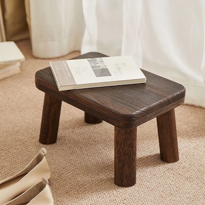 Solid wood shoe changing stool with distressed finish and bracket structure in a living room setting