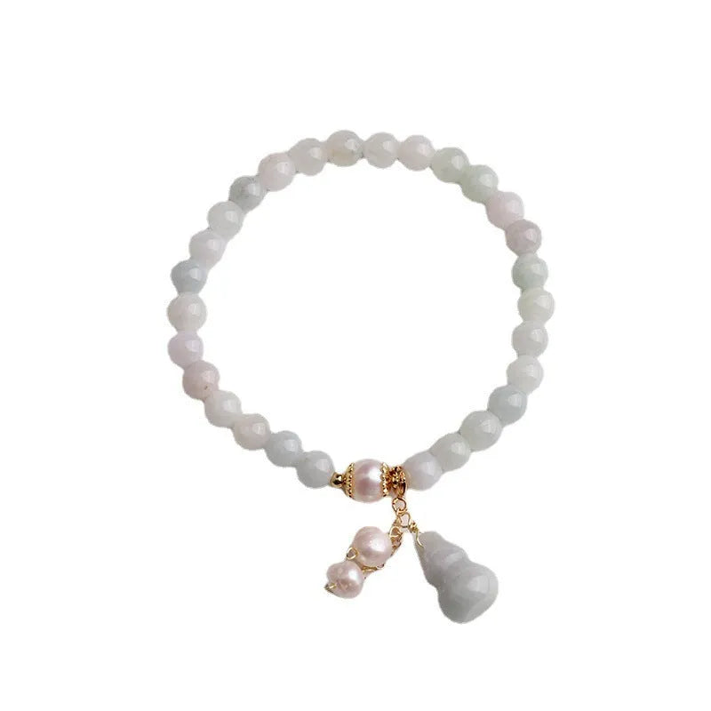 A handcrafted natural emerald jade bracelet with a detailed gourd charm, presented on a white background.