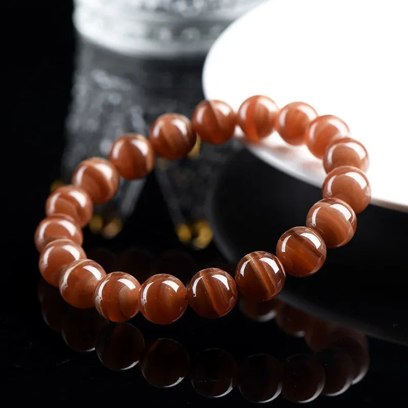Natural old mine rhodochrosite round bead bracelet with Ruyi symbol on a wrist.