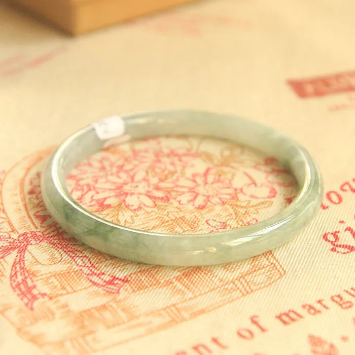 Green geometric Chinese style jade waxy bracelet shown on a wrist, highlighting its 10mm width and detailed pattern.