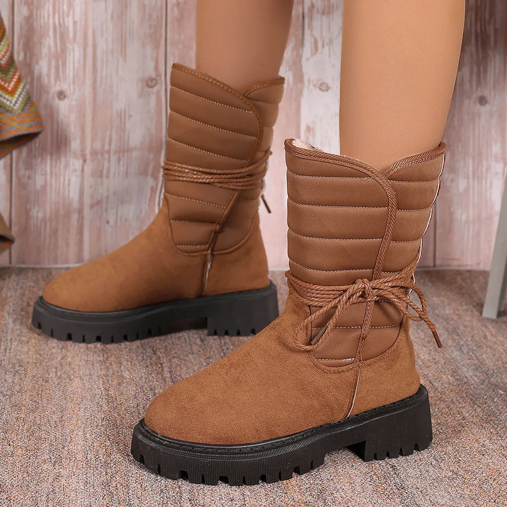 Women's black suede snow boots with chunky heel and lace-up design showing fleece lining