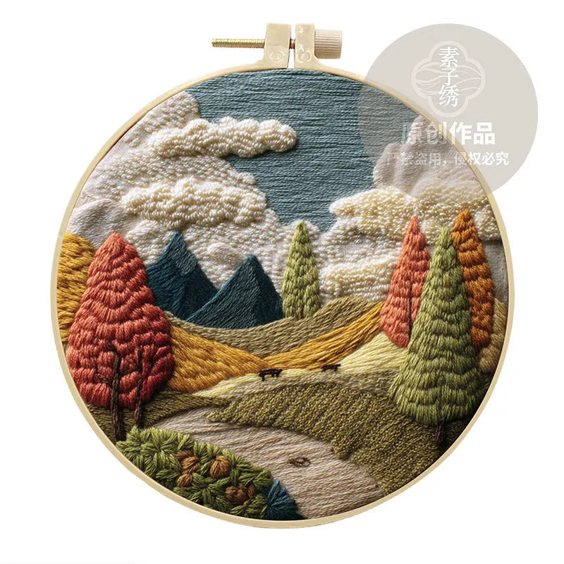 Landscape embroidery DIY kit with cotton fabric, printed pattern, embroidery frame, needles, and thread on wooden surface