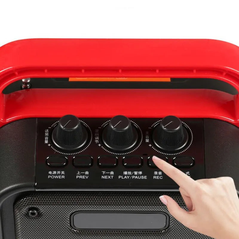 Portable black Bluetooth speaker with a wireless microphone, remote control, and carry strap.