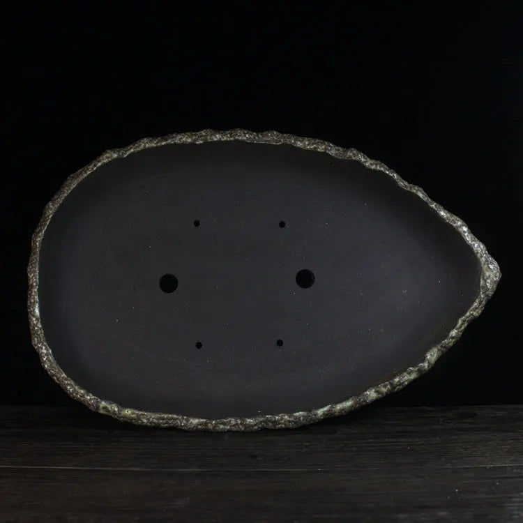 Handmade purple clay flower pot with sculptural shape on wooden floor