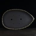 Handmade purple clay flower pot with sculptural shape on wooden floor