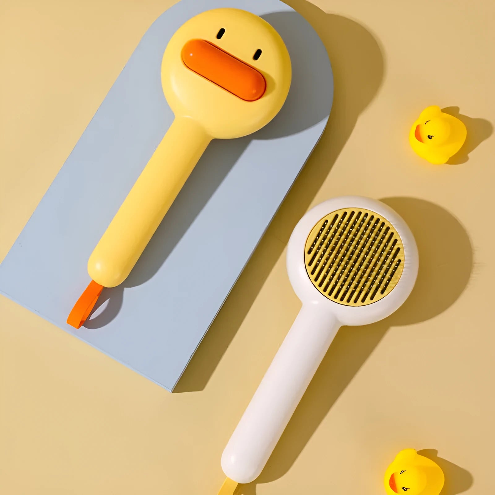 Small yellow duck-shaped pet grooming comb with open sections and needle bristles