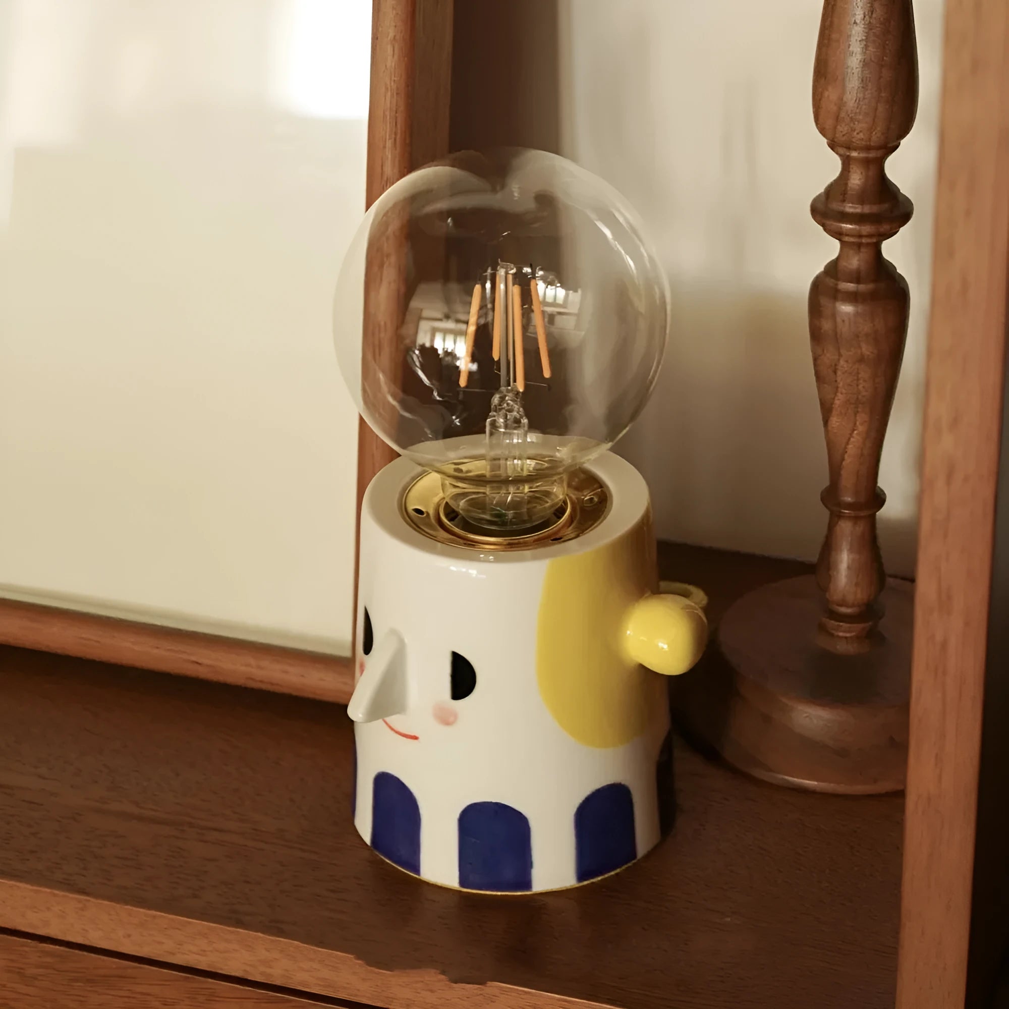 Handmade ceramic bedside lamp with ball-shaped headlight design on wooden surface