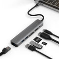 Silver USB C 7-in-1 hub dongle with SD card slot, micro SD slot, and USB C PD charging port.