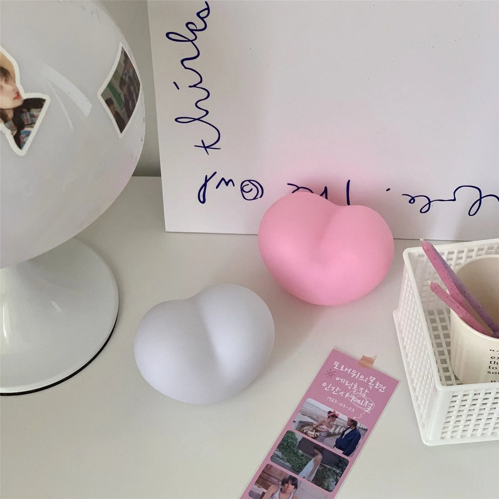 White and pink vinyl trumpet-shaped atmosphere lamps glowing with warm light on a dark surface.