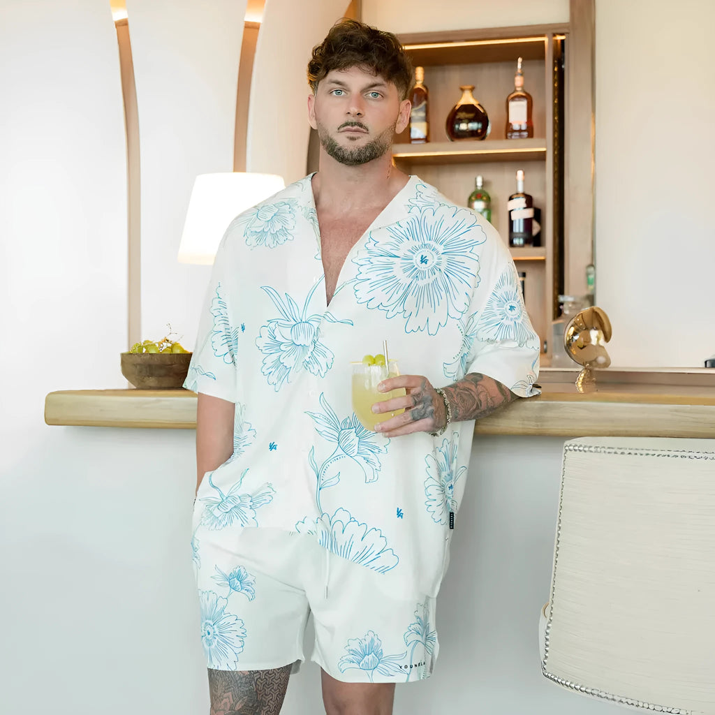 A man's loose-fitting, short-sleeve casual top with a floral print, shown in a neutral colour.