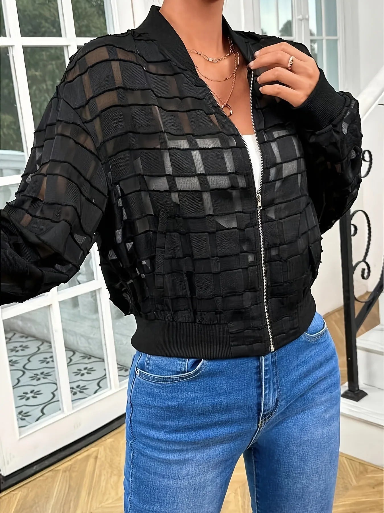 Black women's jacket with geometric pattern and semi-transparent polyester fabric showing zipper closure