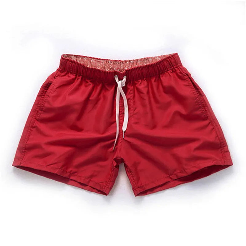Men's straight leg beach shorts in polyester, shown in multiple colours including fluorescent yellow and navy blue.