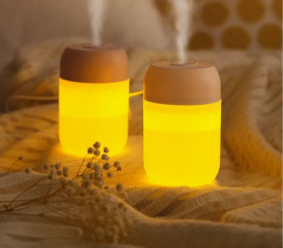 White cylindrical mini humidifier with USB cable on wooden desk