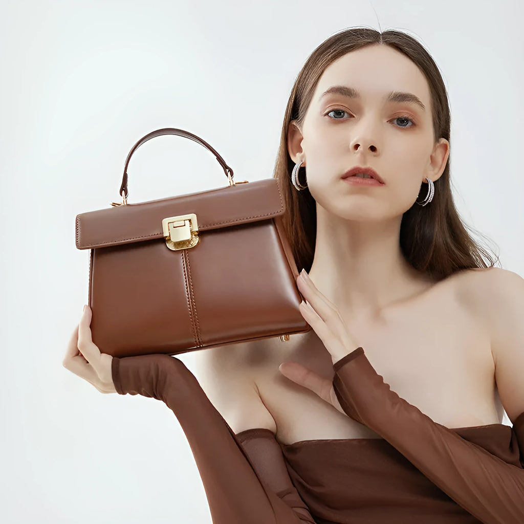 Black genuine leather women's shoulder bag with clasp closure showing square shape and adjustable strap