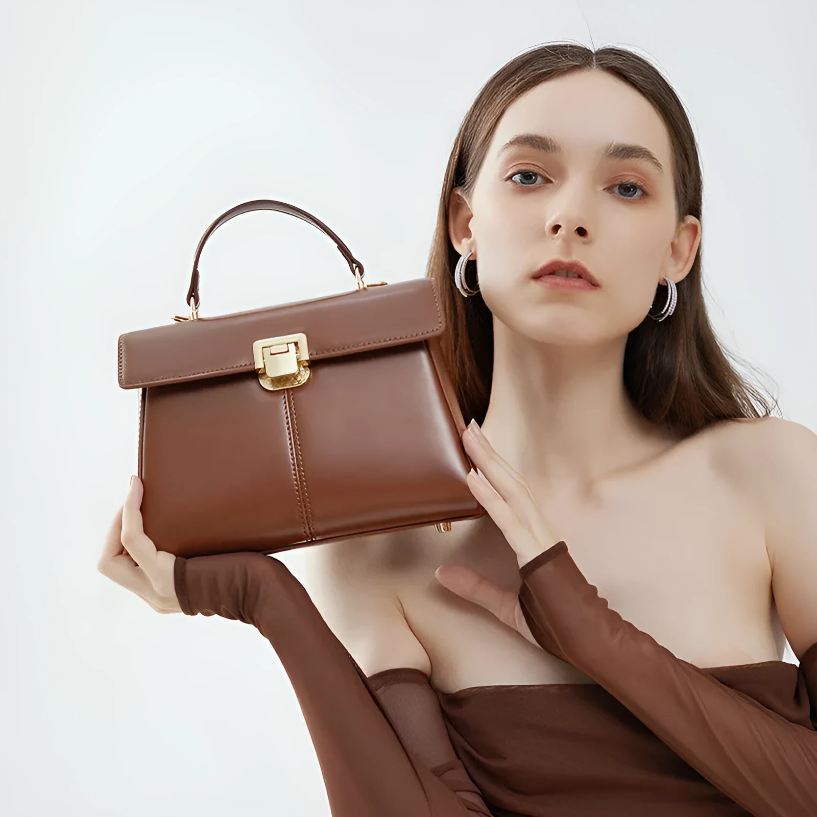 Black genuine leather women's shoulder bag with clasp closure showing square shape and adjustable strap