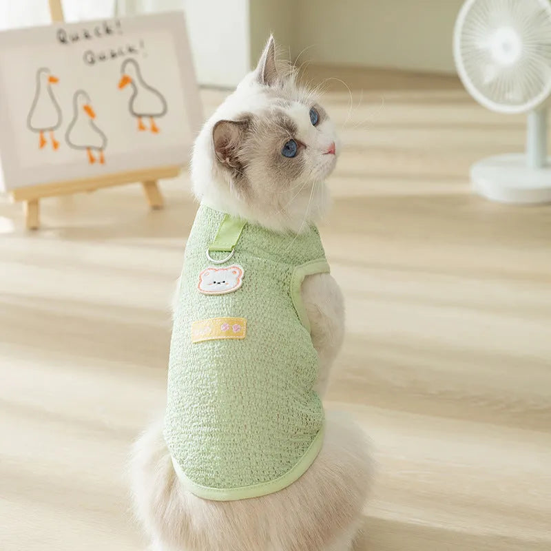 Green knitted cat clothing with a bear patch, showing hollowed-out breathable fabric.