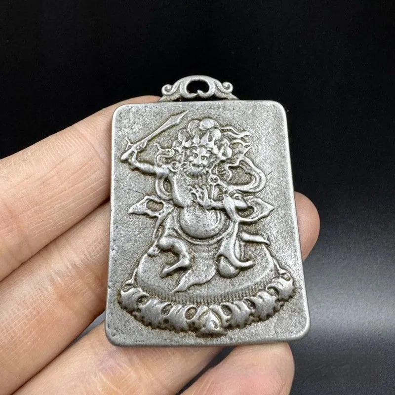Close-up of an antique iron pendant depicting the Aryaacalanatha Yamantaka icon in a Chinese geometric style.