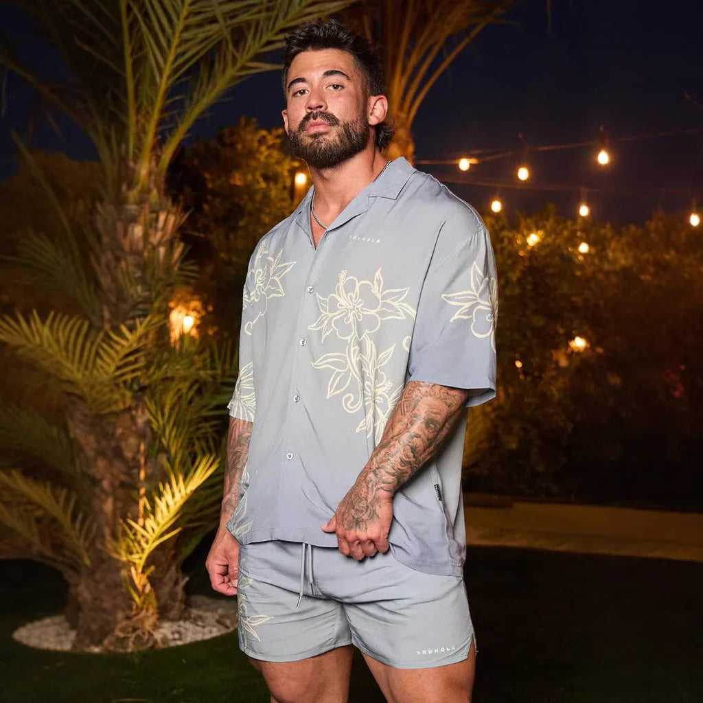 A man's loose-fitting, short-sleeve casual top with a floral print, shown in a neutral colour.