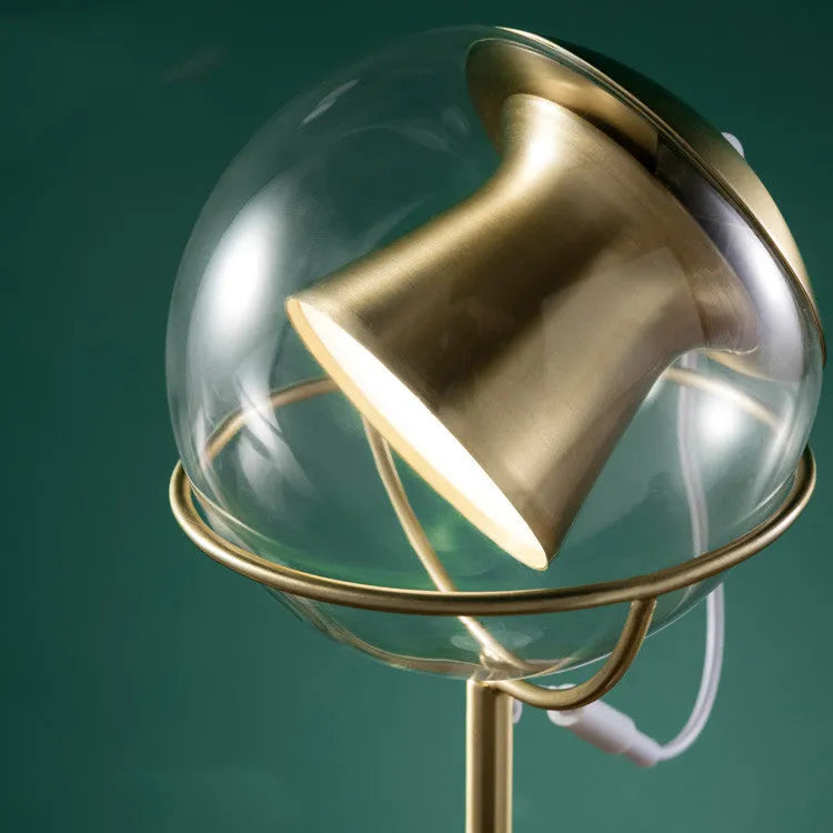 Clear glass dimmable desk lamp with touch switch on a wooden desk.