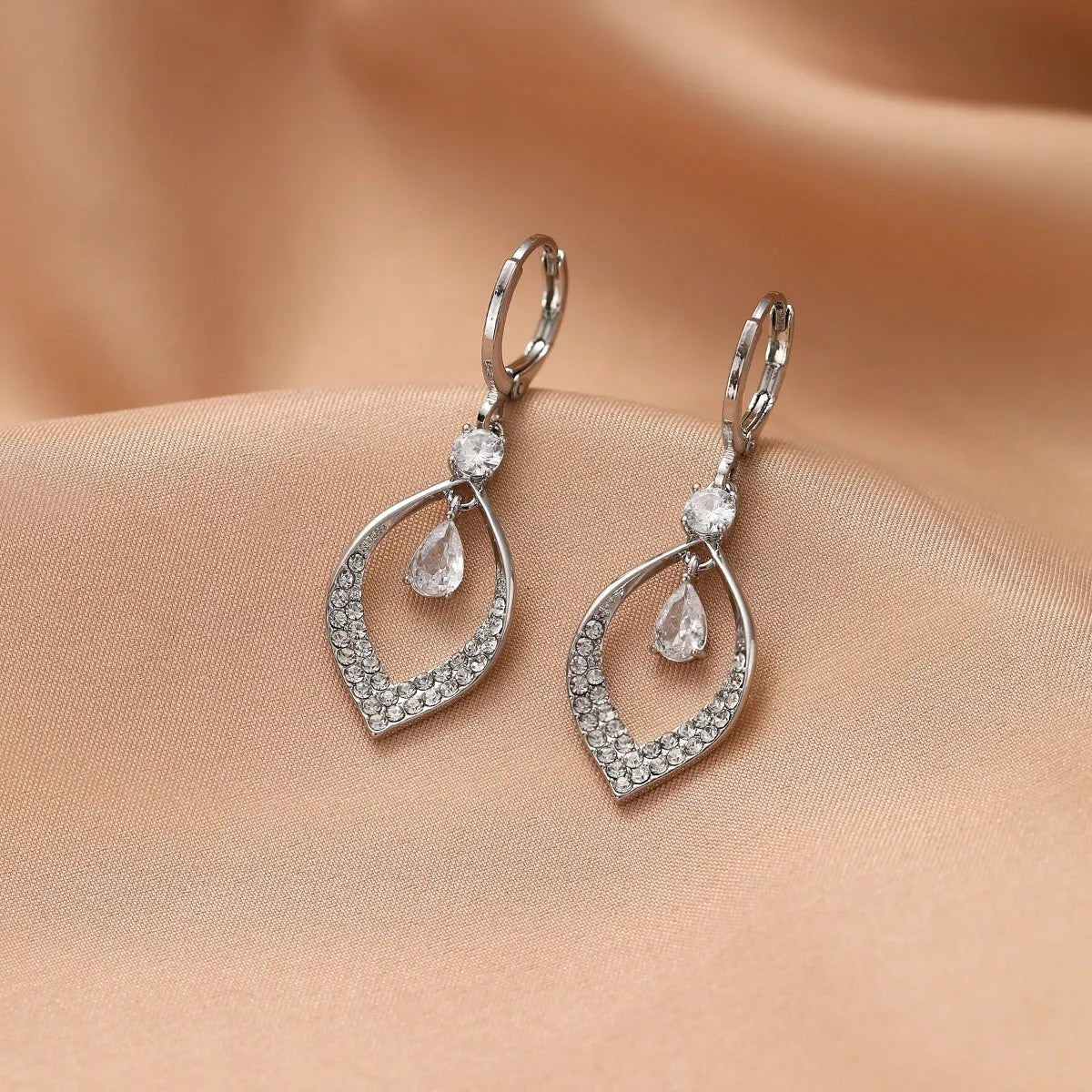 A pair of women's zircon teardrop tassel earrings with gold metal buckles on a white background.