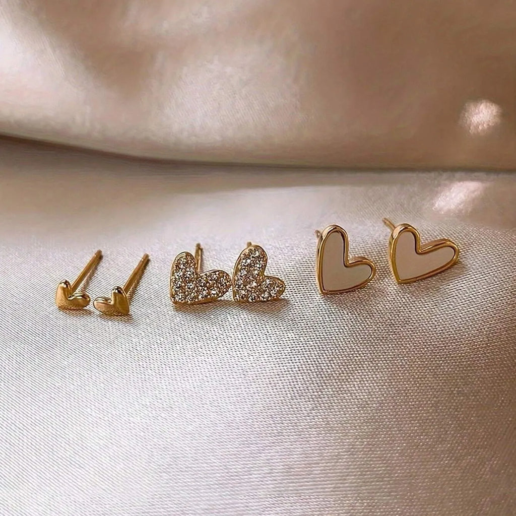 Three pairs of heart-shaped girly earrings in gold, black, black and white, and pink colours