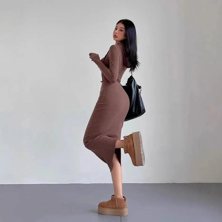 A woman wearing a light grey hooded long sleeve sheath dress with a high waist.