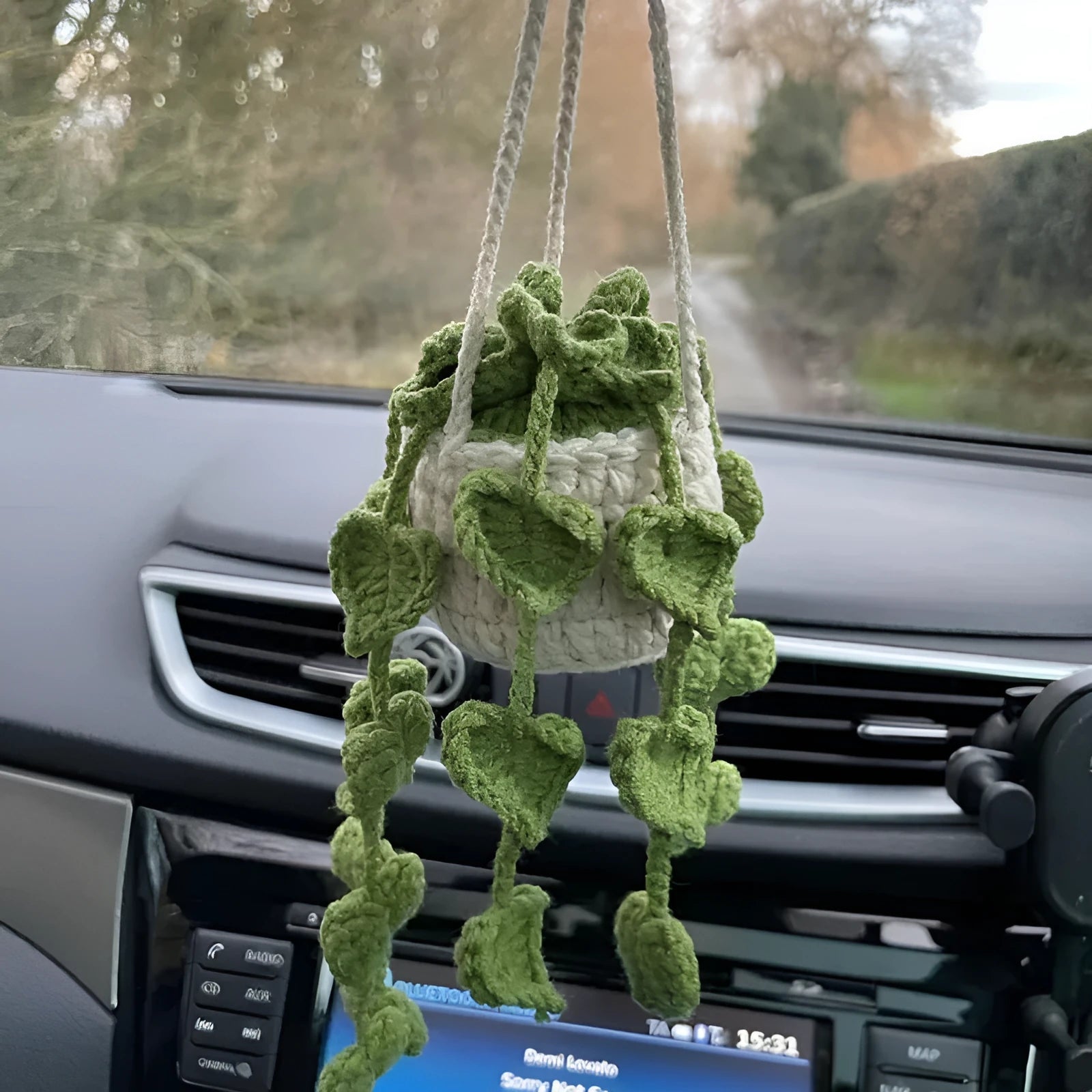 Green and white hand-knitted car plant ornament with a hanging cord on a basin-shaped base.
