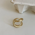 Geometric open ring for women with three-dimensional interlaced design in matte gold or silver metal.
