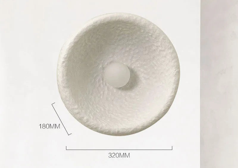 Japanese modern simple wall lamp with white resin shade in three size options on a plain wall.