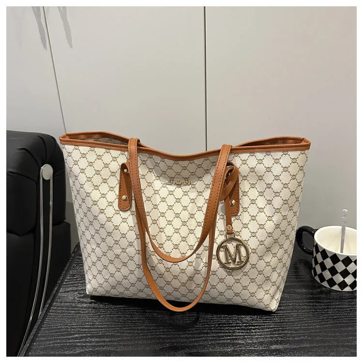 Women's black PU leather shoulder bag with sewing thread detail on a table.