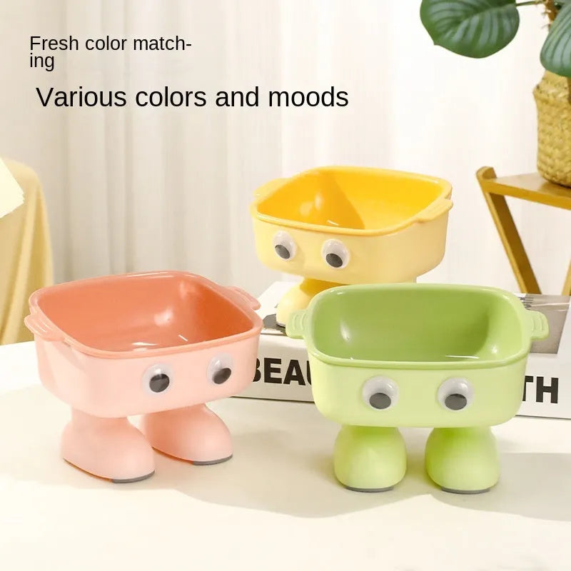 Green elevated cat bowl with 15-degree tilt, detachable inner dish, and cartoon robot design on a table.