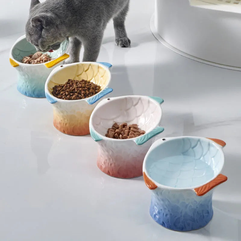 Set of blue, green, pink, and yellow ceramic fish shaped cat bowls with a tilted design.