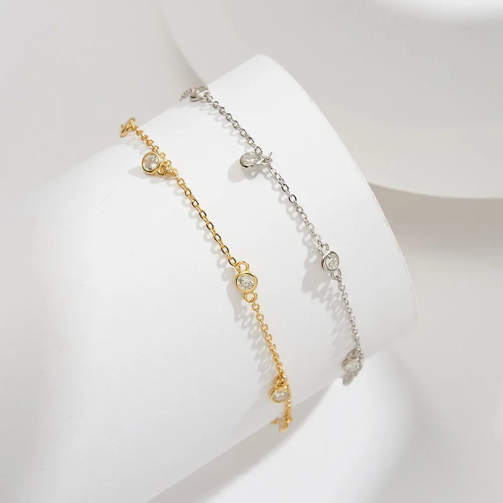 Women's silver geometric zirconium pendant anklet on an ankle, shown in gold and platinum colour options.